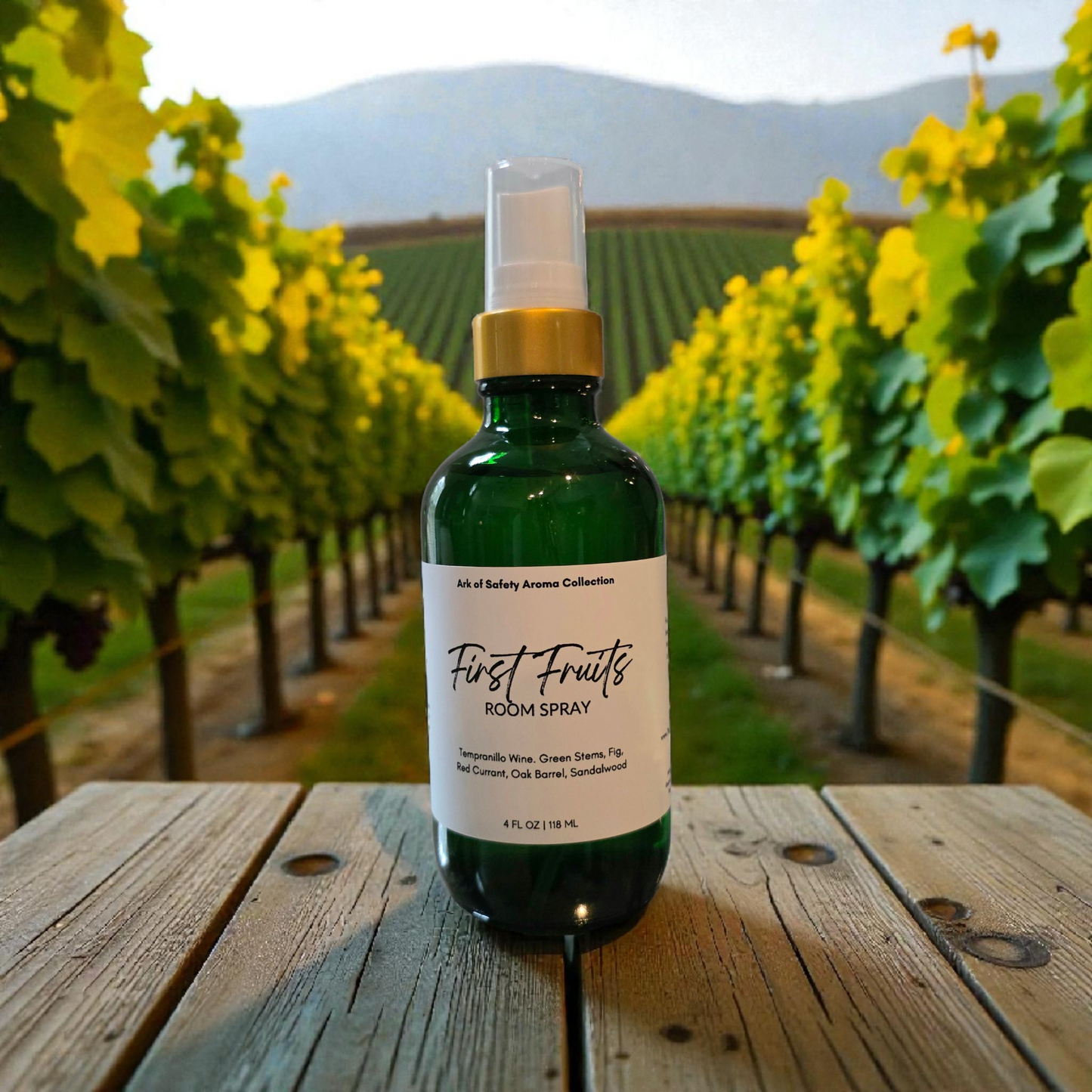 Bottle of 'First Fruits' room spray on a wooden table with vineyard background
